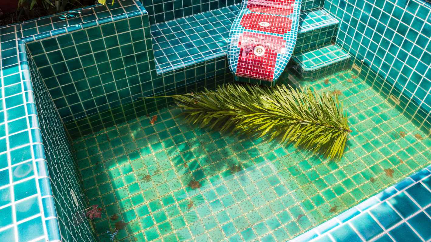 A red and blue boat sitting on top of a green tiled pool
