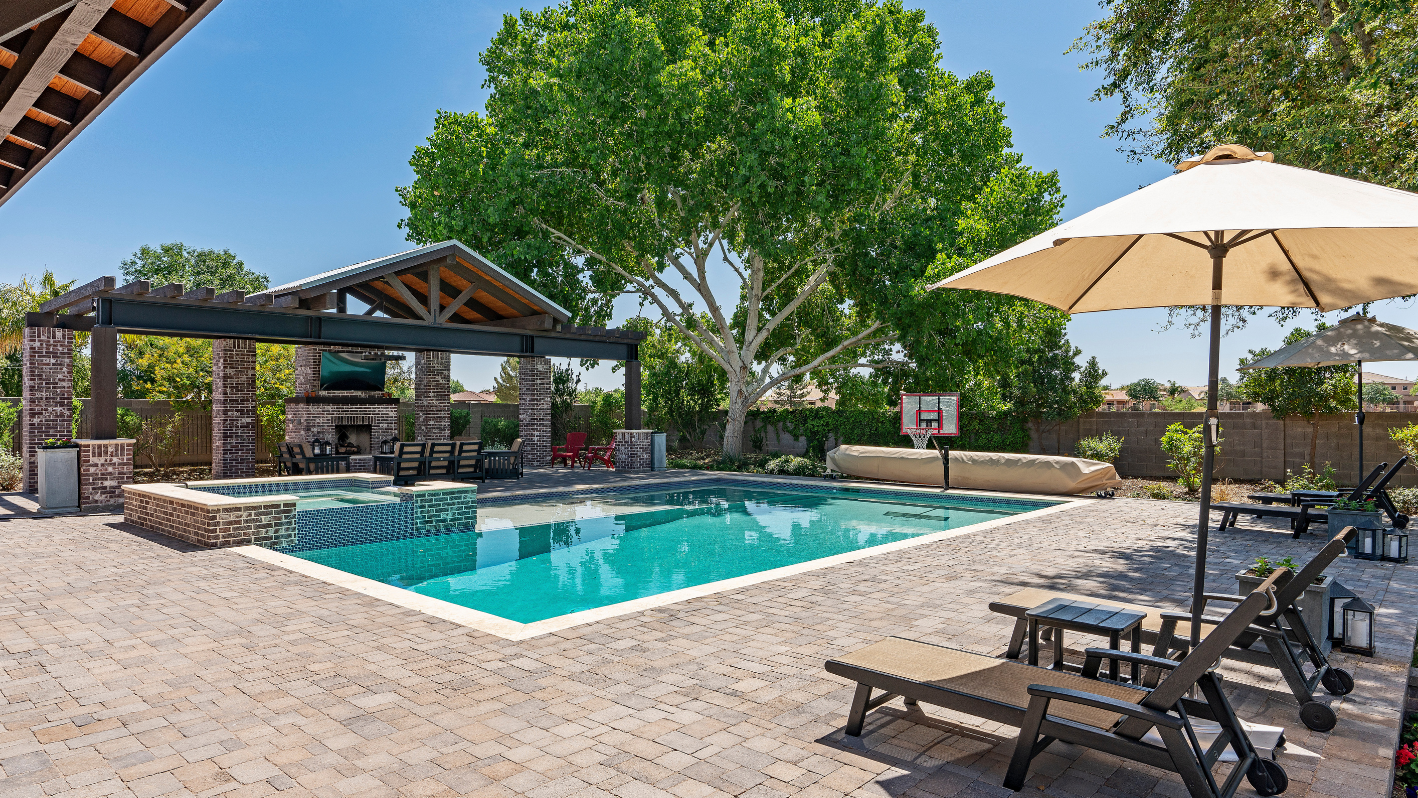 A backyard with a pool and patio furniture